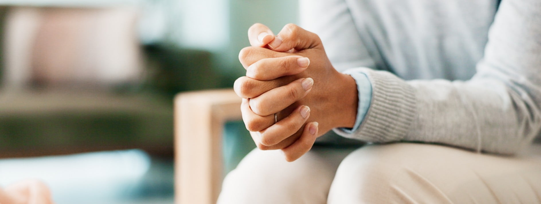 a picture of one persons hands interlocked as they sit in a chair.
